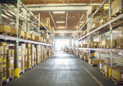 Forklift trucks and drivers working in distribution warehouse aisle